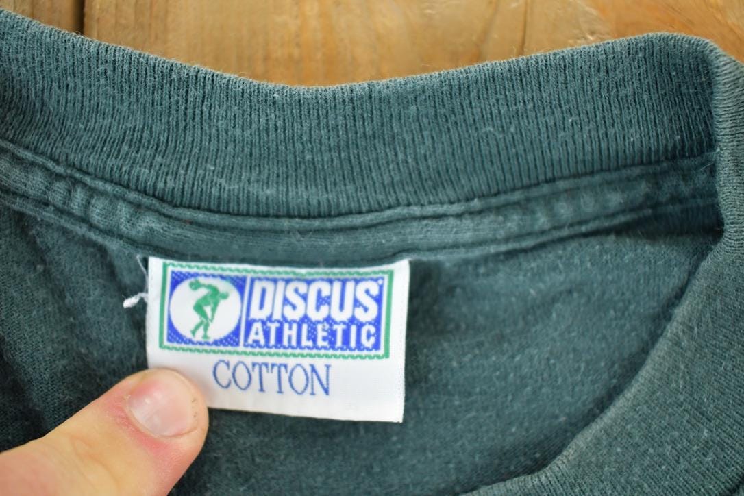 Vintage 1990s Discuss Athletic Souvenir Single Stitch Graphic Print T-Shirt Men's XL from propervintagecanada