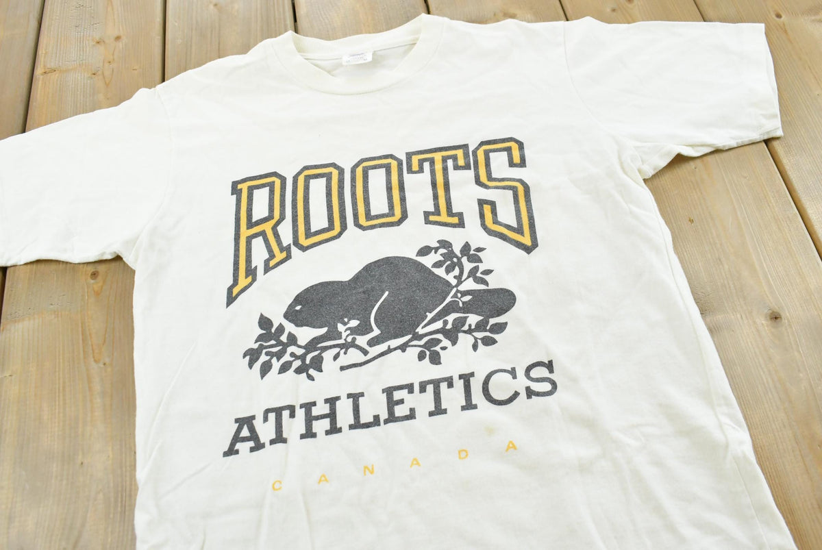 Vintage 1990s Roots Athletics Graphic T-Shirt Men's M from propervintagecanada